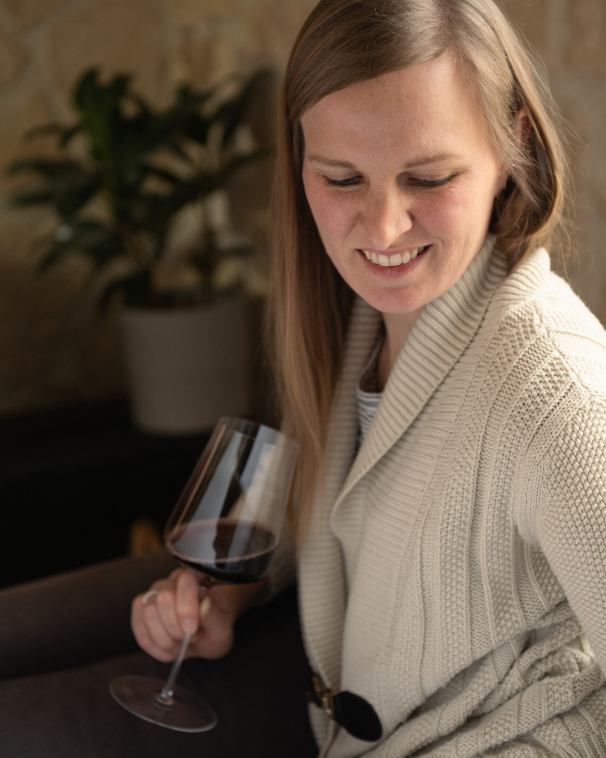 Holding a glass of wine in a cozy sweater looking down