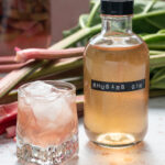 stems of rhubarb, a small bottle and glass of rhubarb gin over ice