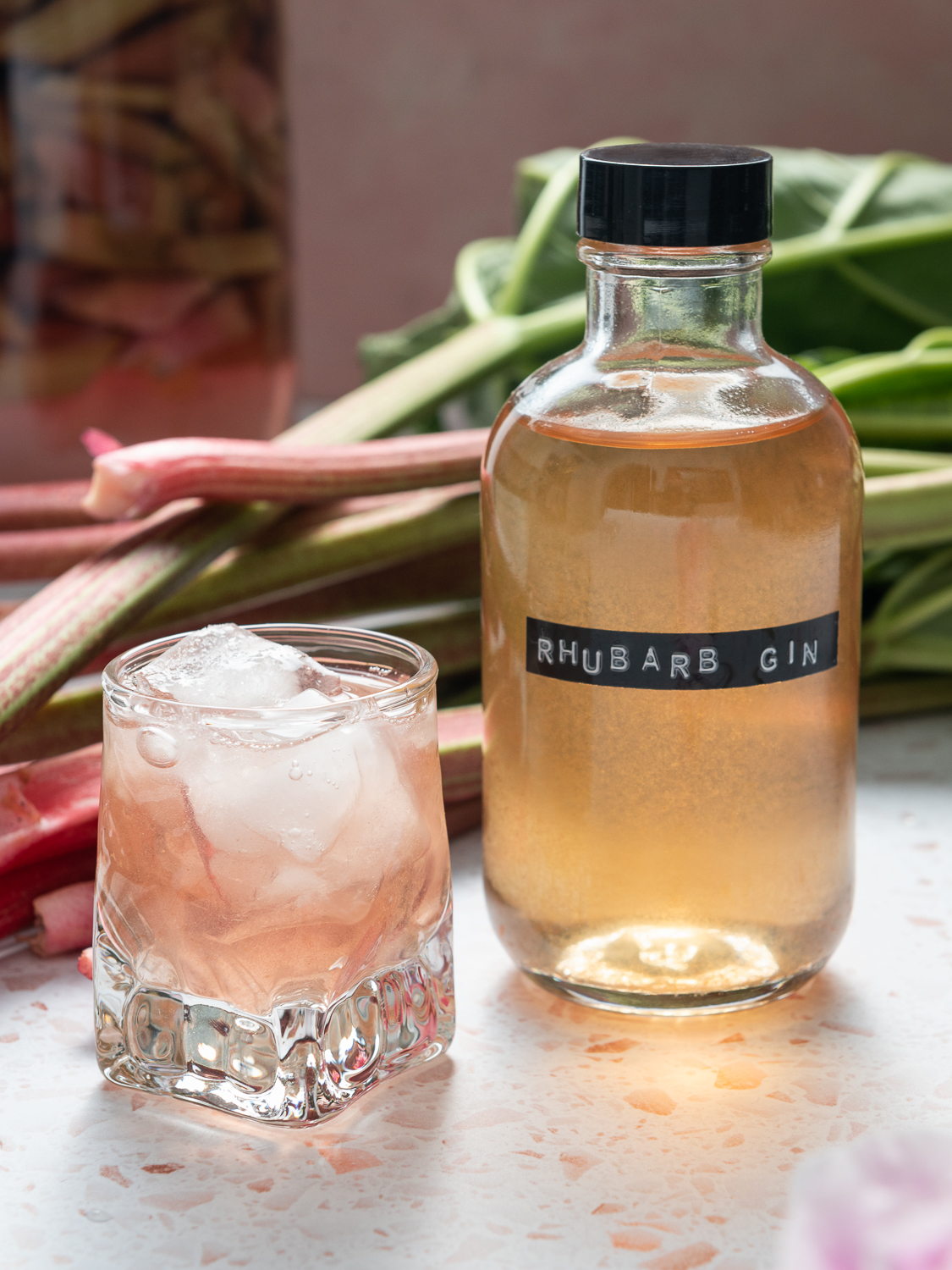 stems of rhubarb, a small bottle and glass of rhubarb gin over ice