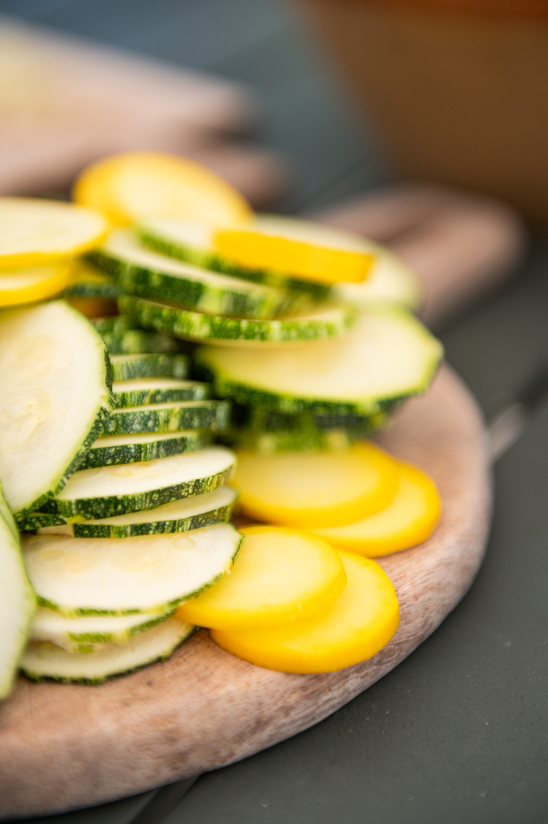 sliced yellow and romanesco courgettes on a round cutting board for french courgette tart 