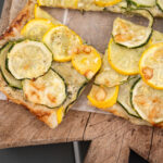 Baked French courgette tart sliced up and on a rustic wooden cutting board