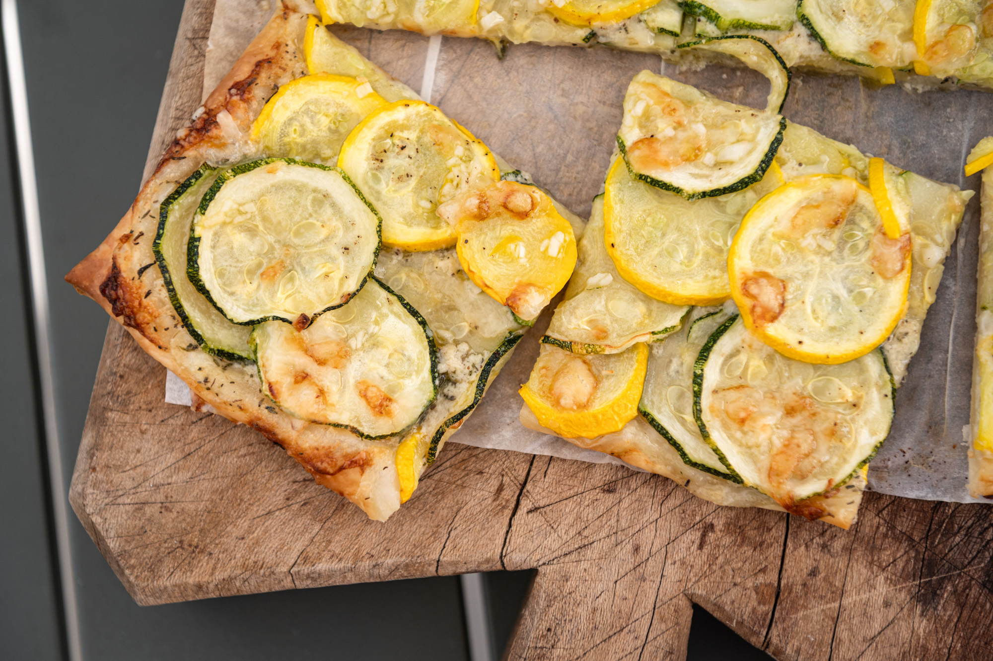 Baked French courgette tart sliced up and on a rustic wooden cutting board