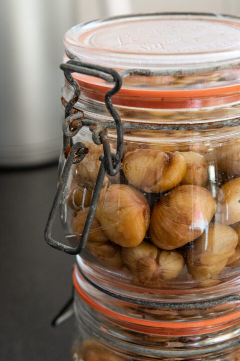canned jars of fresh chestnuts stacked on a stone countertop