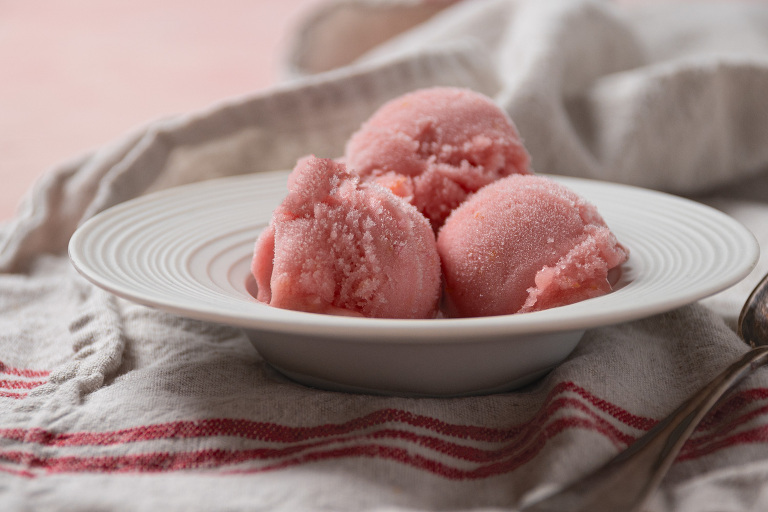 bowl with three scoops of rhubarb elderflower sorbet on a linen tea towel